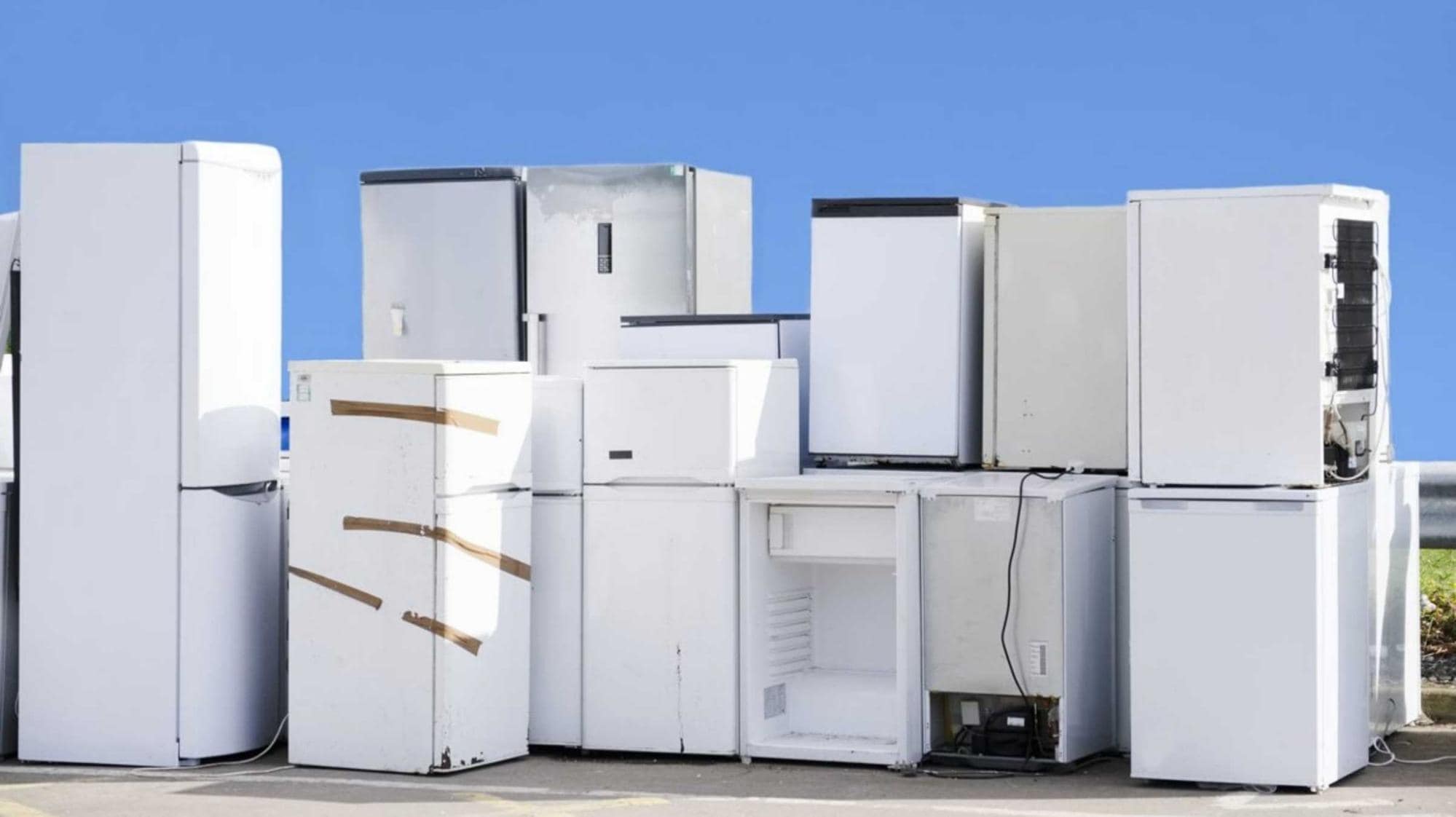 A stacked collection of refrigerators and various household appliances in a cluttered arrangement.