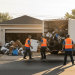Professional photo of Jiffy Junk’s licensed pros loading a white appliance and household debris into a large removal truck on a suburban driveway, providing a reliable solution for those searching for the best cheap local junk haulers in their area.