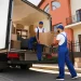 Furniture removal team loading an old couch into a box truck during a same-day bulk junk pickup at a residential home