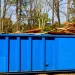 View of a large roll off dumpster filled with construction wood debris at a job site, showing affordable construction waste dumpster rental services near me.