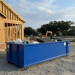 A large 12-yard blue dumpster rental filled with construction debris sitting in front of an ongoing construction.