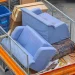 An image of old furniture disposal with blue couches, boxes, and household junk loaded into a truck for removal, showing how to get rid of and dispose of old furniture near me