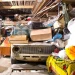 An image of a cluttered garage filled with boxes, old furniture, tools, and stored items, illustrating how to declutter and empty your garage fast with effective cleanout and organization tips