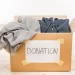 An image of a donation box filled with old clothes and labeled “donation,” illustrating how to get rid of old clothes through clothing donation or textile recycling to reduce waste and support reuse.