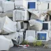An image of a large pile of old desktop computers, CRT monitors, and outdated computer equipment awaiting e-waste recycling.