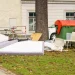 An image of a discarded mattress and furniture beside dumpsters in Greensboro.